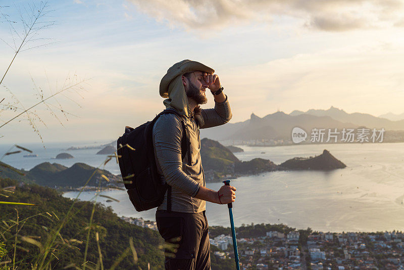 A hiker man enjoying his accomplishment of reaching the top of the mountain, and enjoying the splendid view